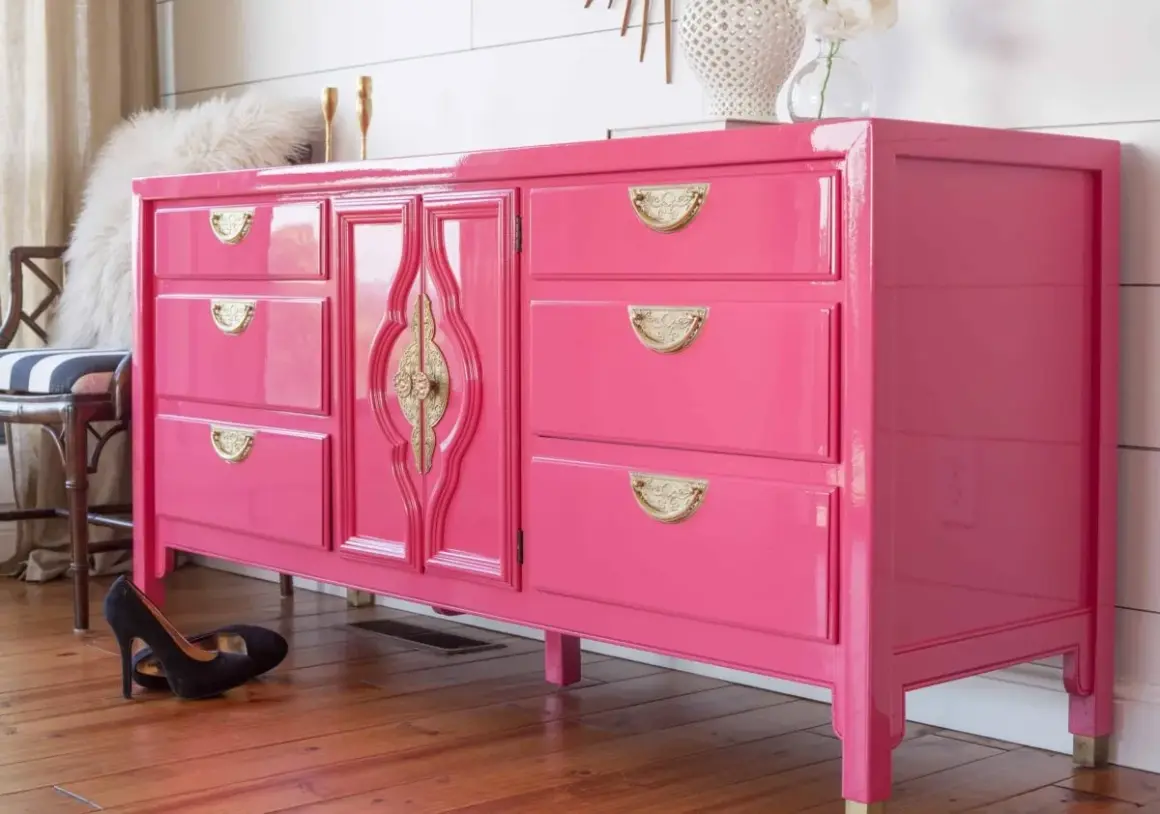 Comò rosa brillante con maniglie dorate, un esempio di come laccare un mobile già verniciato per un look audace.