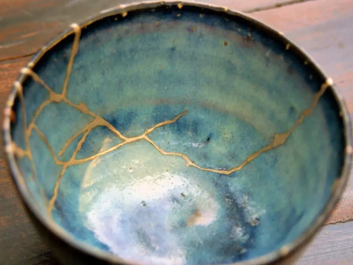 Ciotola blu con crepe dorate, un esempio di tecnica kintsugi che celebra le imperfezioni.