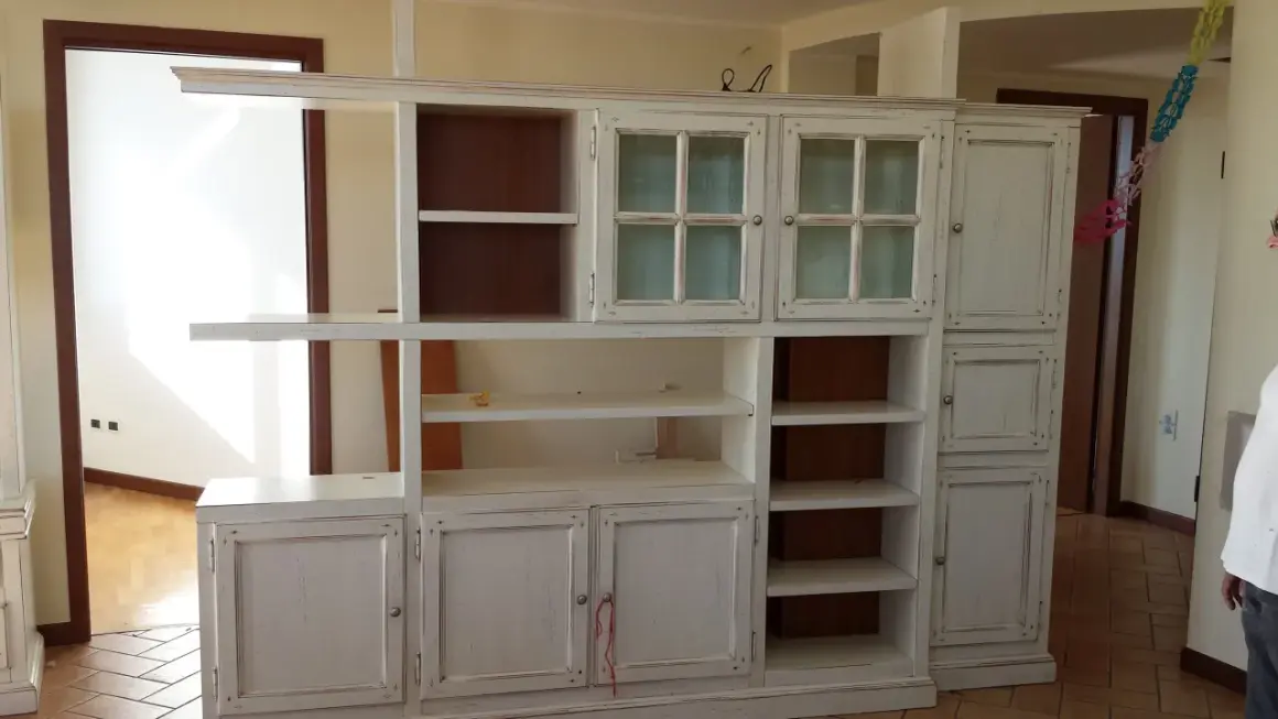 Mobile libreria in stile decapato, con ante a vetro e cassetti, che evoca un fascino vintage.