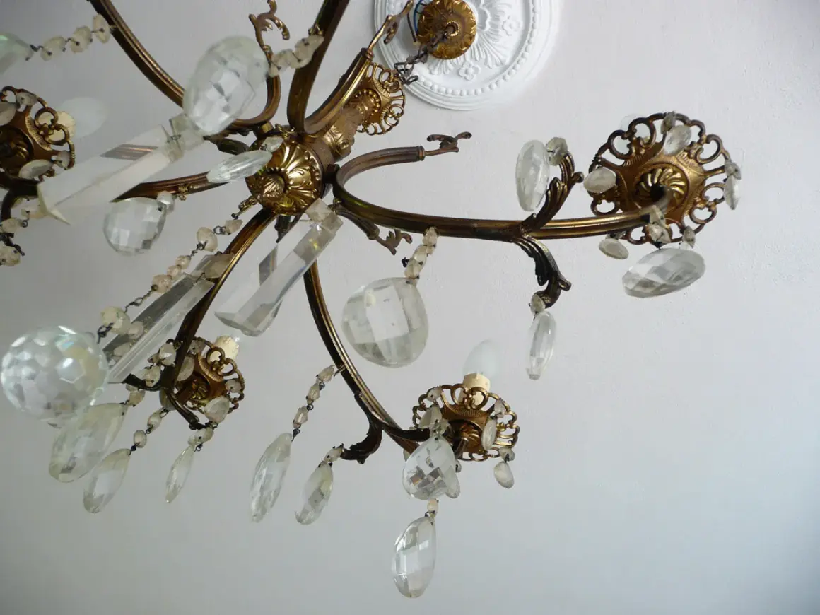 Dettagli di un lampadario a gocce in ottone, con cristalli trasparenti e perline. Un'idea per come rimodernare un lampadario a gocce con un tocco di eleganza.