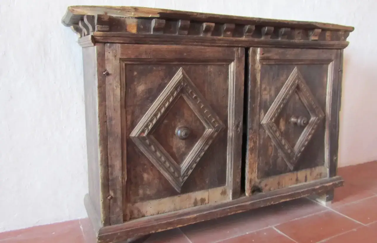 Mobile antico in legno scuro, con due ante decorate a rombo, pronto per essere restaurato.