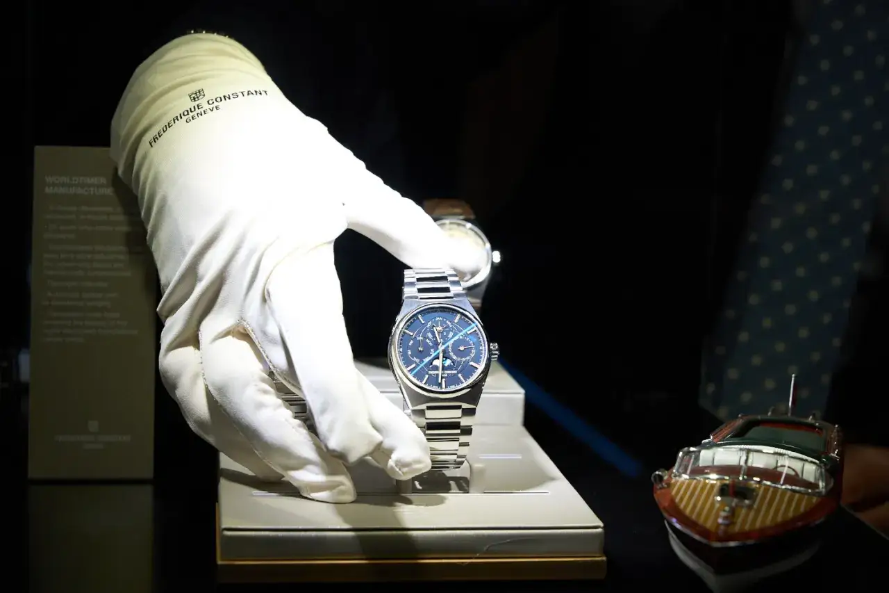 Guanto bianco presenta un orologio da polso blu con quadrante complesso, in una fiera di orologi.