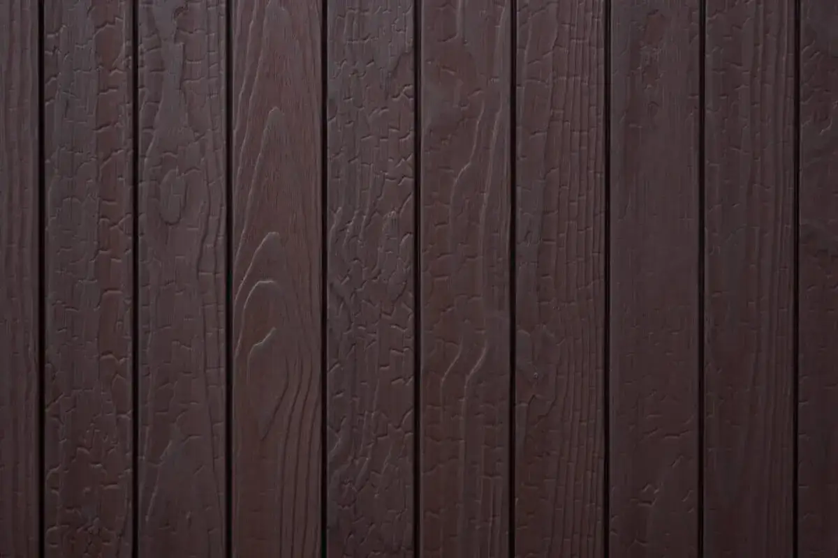 Tavolato scuro con venature evidenti, che ricorda il legno bruciato per il suo aspetto vissuto e le crepe superficiali.