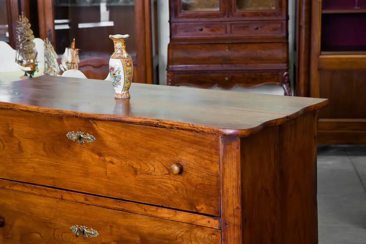 Un mobile in legno scuro, con un vaso decorato in primo piano. Perfetto per chi vuole imparare come antichizzare un mobile e dargli un tocco vintage.