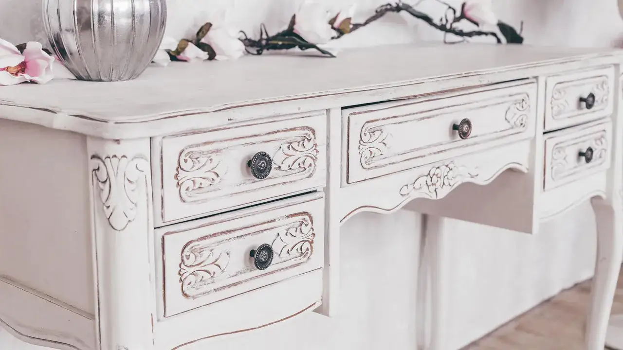 Un tavolino da toeletta bianco con dettagli intagliati, un classico esempio di pittura shabby fai da te.