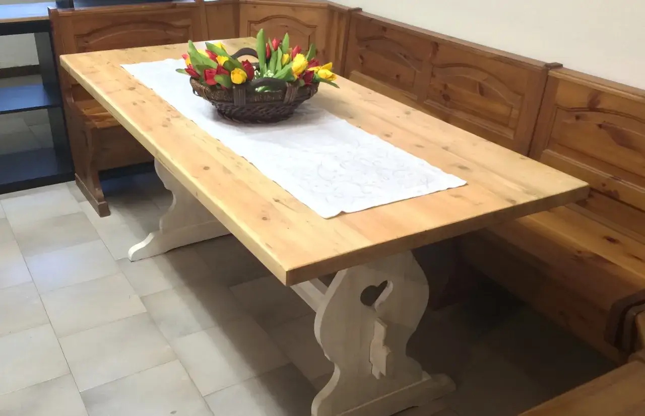 Un tavolo in legno grezzo, con panche in legno scuro, pronto per essere trasformato con un tocco di colore e creatività.