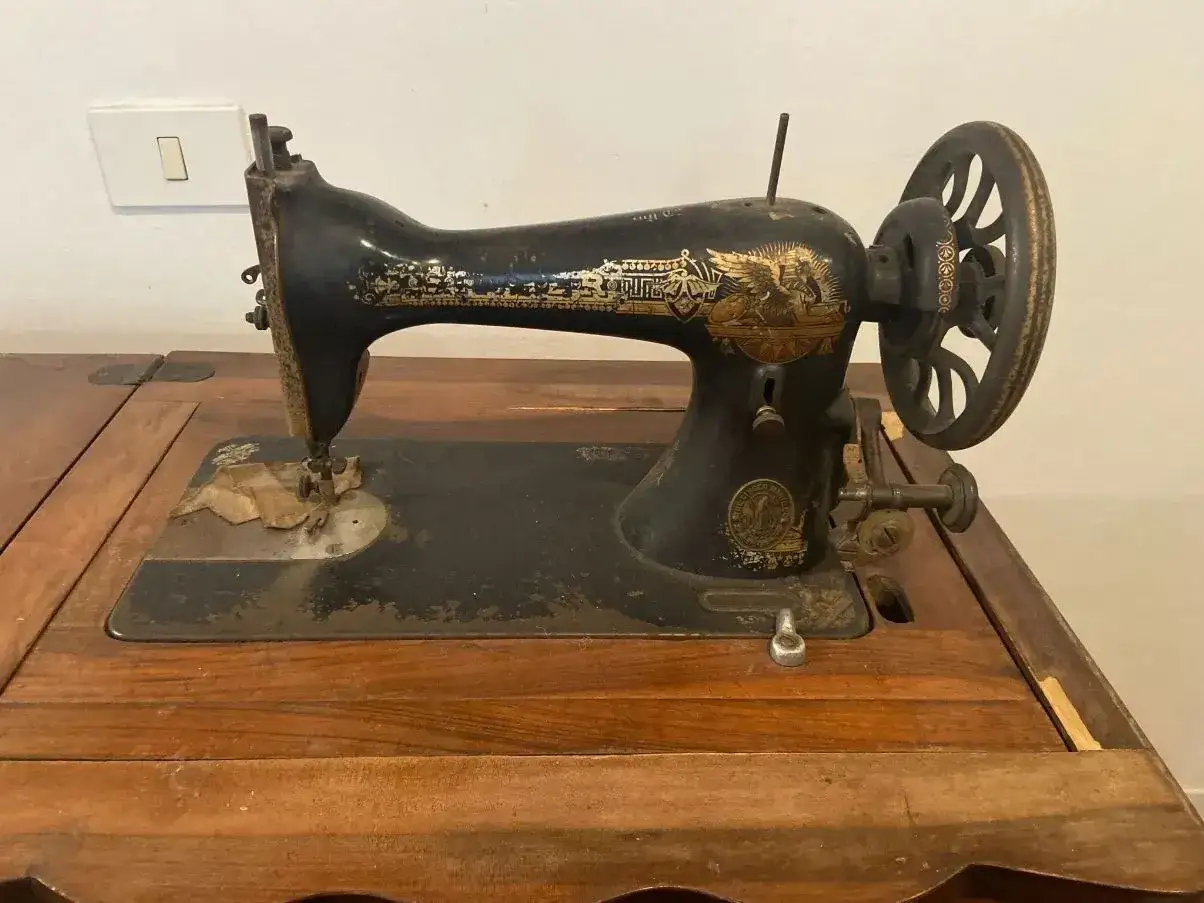 Macchina da cucire Singer antica, con decorazioni dorate e volano, un pezzo da collezione che testimonia il valore macchina da cucire Singer del 1900.