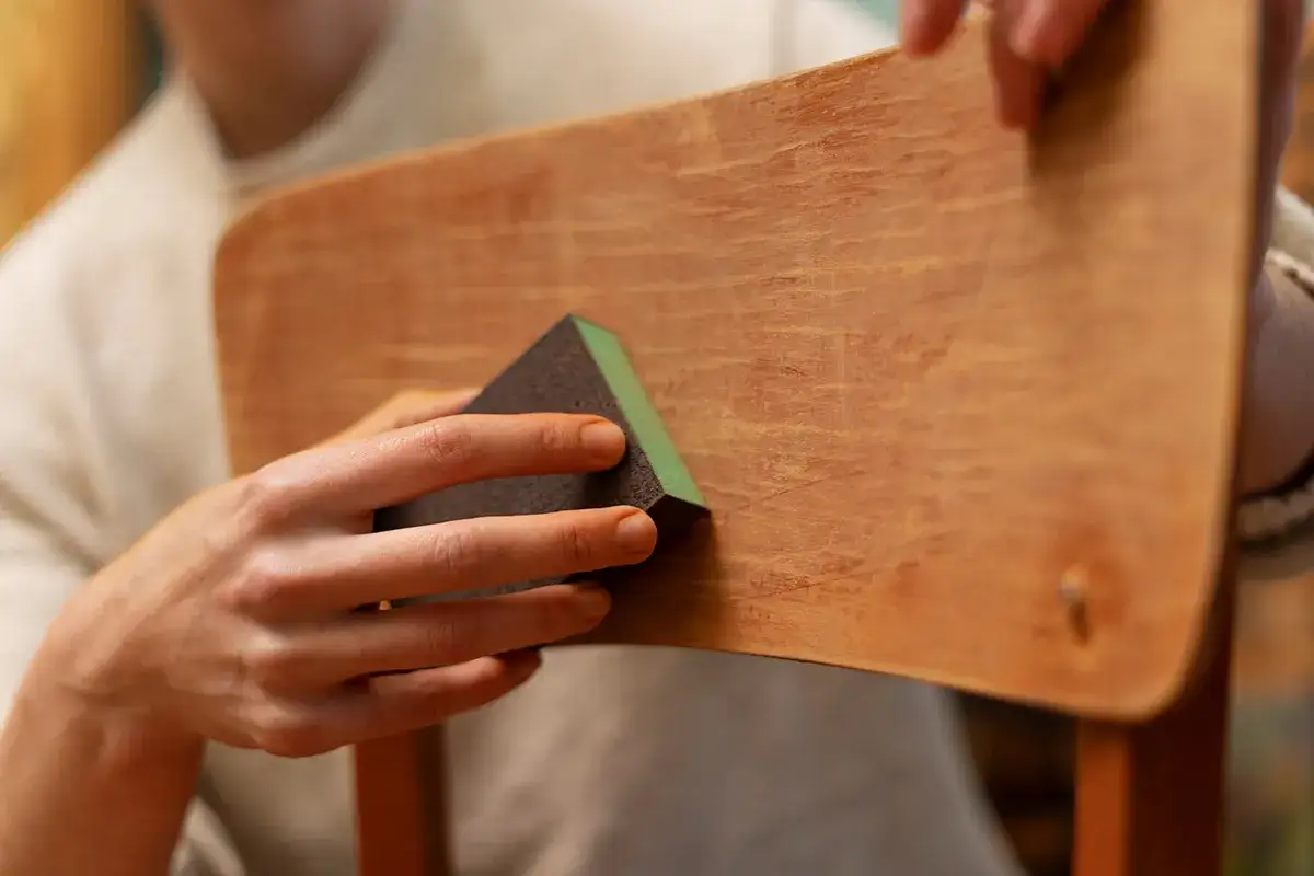 Mani levigano un mobile in legno scolorito, riportando alla luce la sua bellezza naturale.