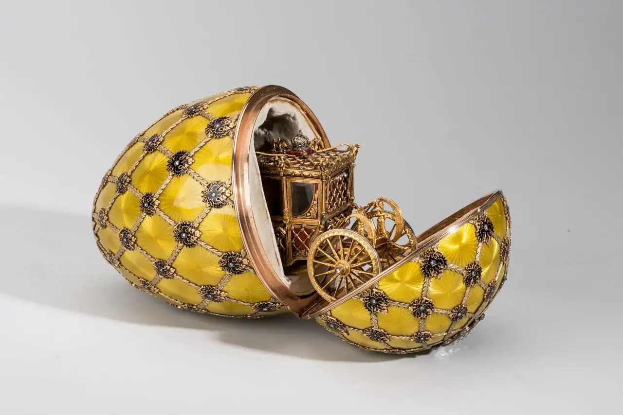 Uova zar dorate, aperte, rivelano una carrozza in miniatura con ruote dorate e una corona.