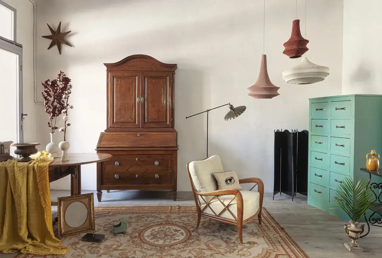 Un mix di idee mobili antichi colorati: un armadio in legno scuro, una cassettiera verde acqua e una poltrona vintage.