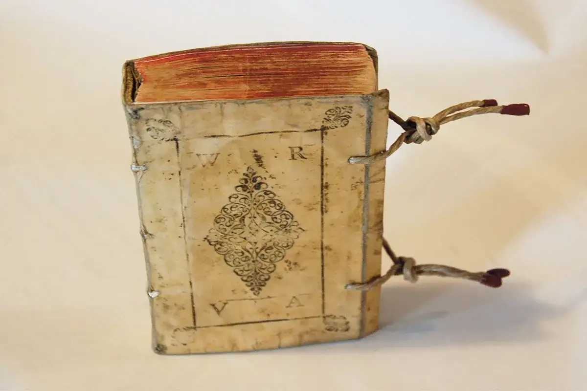 Antico libro rilegato in pergamena, con decorazioni e lacci, testimonianza del valore dei libri antichi del 1700.