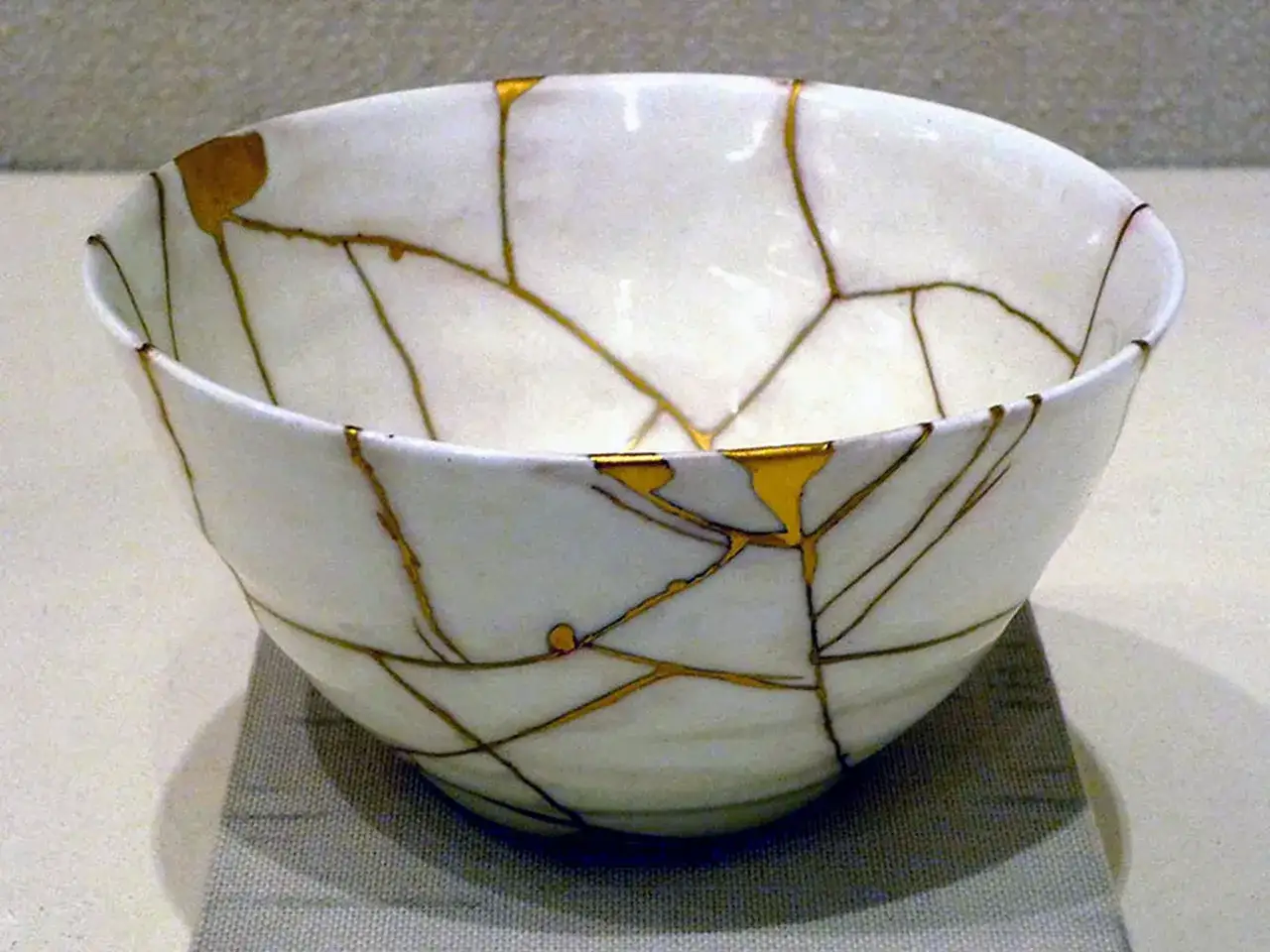 Ciotola bianca riparata con la tecnica del kintsugi, le crepe dorate ne esaltano la bellezza.