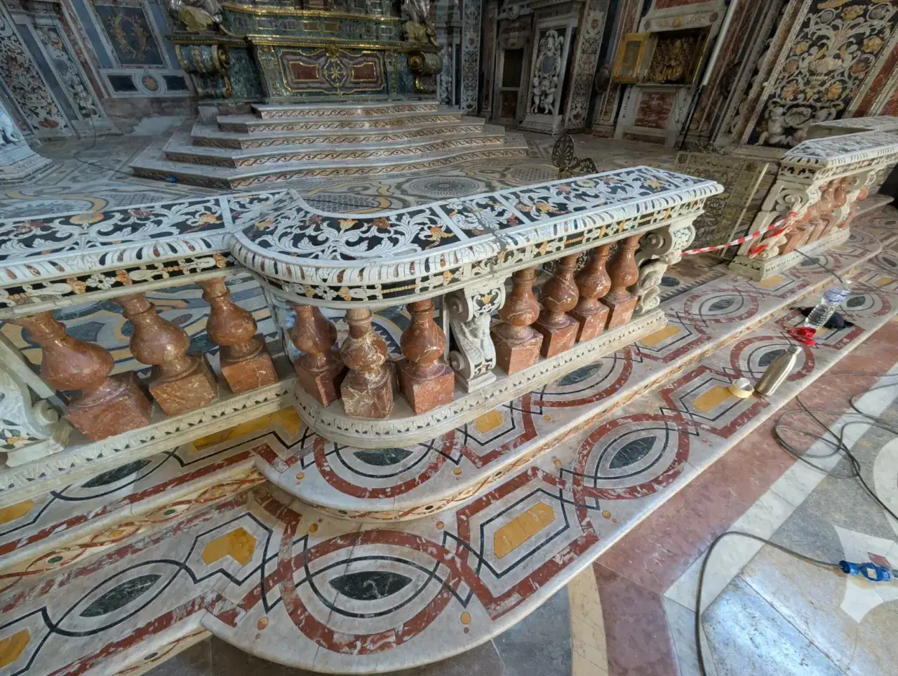 Dettagli di un prezioso restauro marmo in una chiesa barocca. La balaustra intarsiata e il pavimento geometrico mostrano la maestria artigianale.