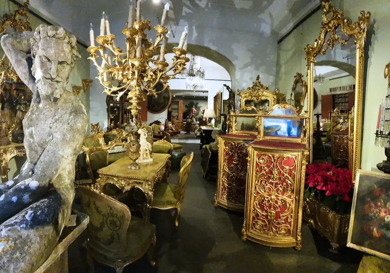 Un negozio d'antiquariato pieno di mobili dorati, statue e specchi. Un luogo dove imparare come diventare antiquario, circondati da tesori del passato.
