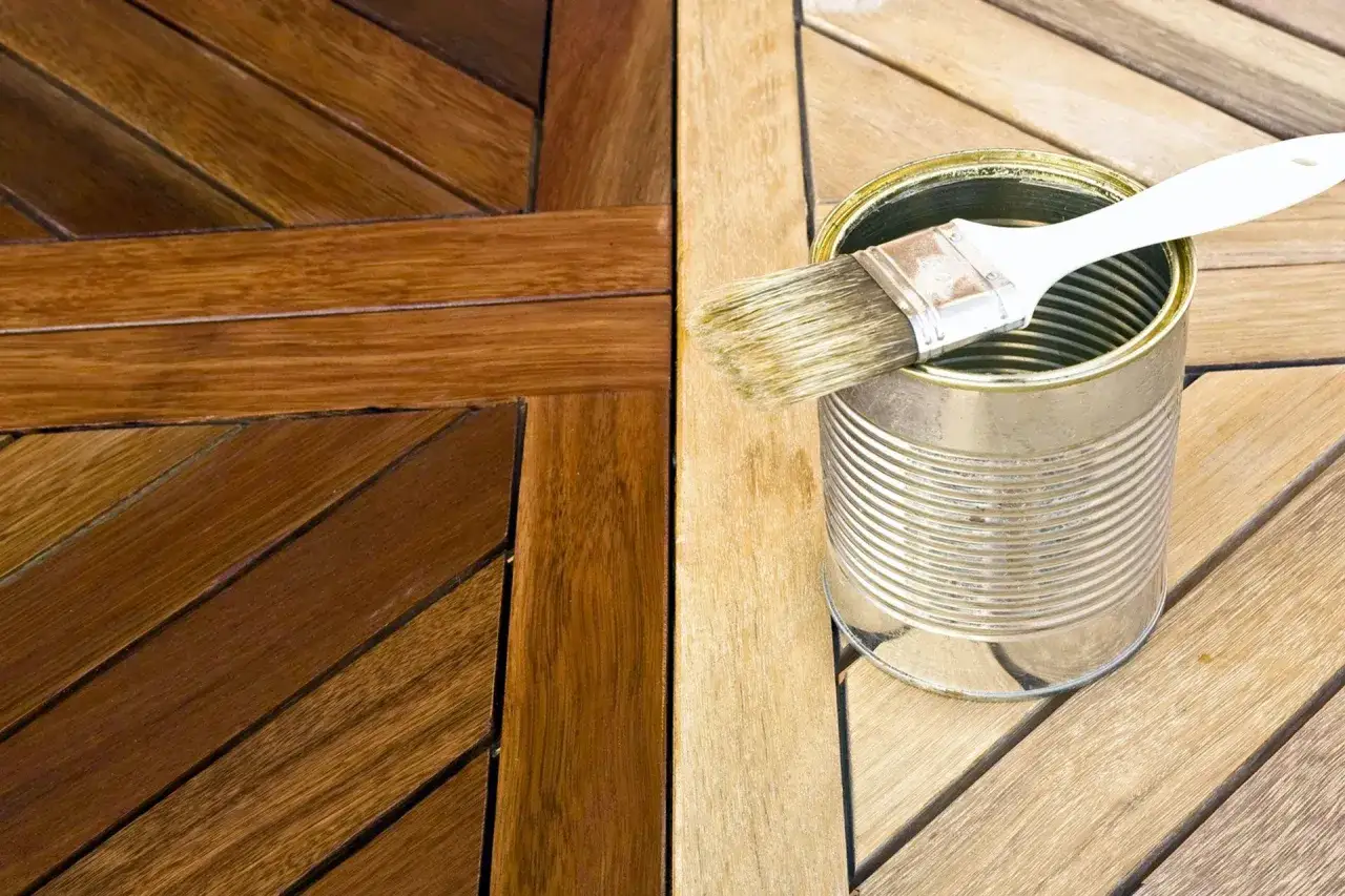 Legno trattato con impregnante, con una latta e pennello pronti per il prossimo passaggio.