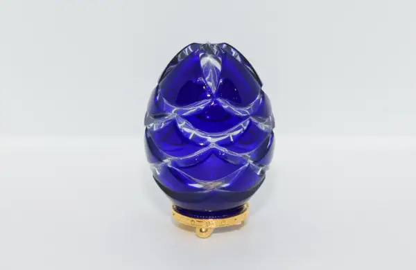 Uovo blu di cristallo intagliato, ispirato agli originali uova Fabergé, su base dorata.