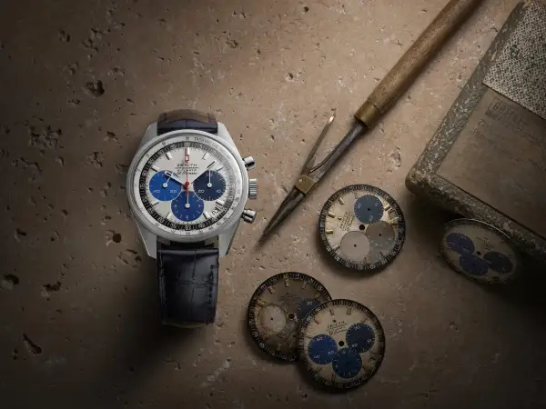 Orologio Zenith El Primero con quadrante bianco e blu, cinturino in pelle blu, circondato da quadranti di ricambio e strumenti da orologiaio.