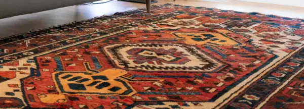 Tappeto persiano usato con motivi geometrici rossi, blu e gialli. Un pezzo d'antiquariato che conserva il suo valore.