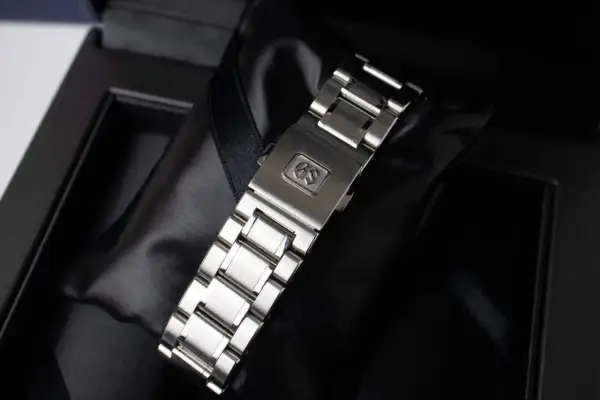 Chiusura di un bracciale per orologio in metallo, con logo GS inciso, pronto per essere indossato.