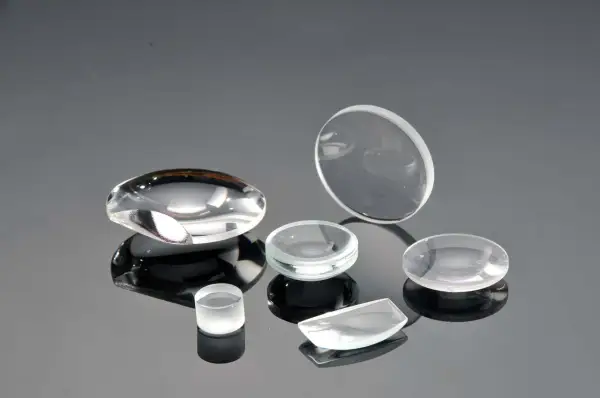 Collezione di lenti ottiche di varie forme, realizzate in vetro minerale o zaffiro, su superficie riflettente.
