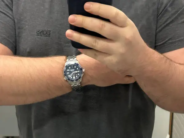 Un orologio da polso con cinturino in metallo, quadrante blu e lunetta blu, indossato su un braccio. La misura lug to lug dell'orologio è perfetta.