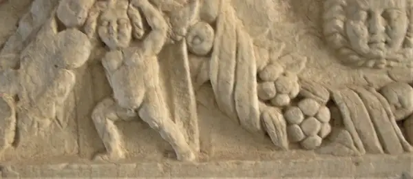Dettaglio di un bassorilievo antico, forse parte di un restauro marmo, raffigurante figure mitologiche con drappeggi e grappoli d'uva.