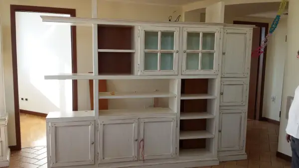 Mobile libreria in stile decapato, con ante a vetro e cassetti, che evoca un fascino vintage.