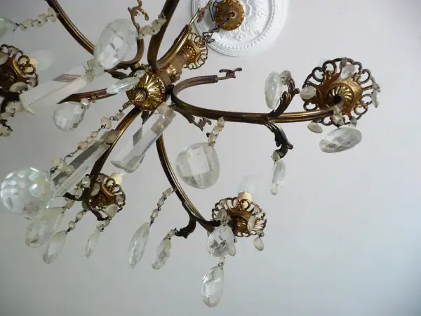 Dettagli di un lampadario a gocce in ottone, con cristalli trasparenti e perline. Un'idea per come rimodernare un lampadario a gocce con un tocco di eleganza.