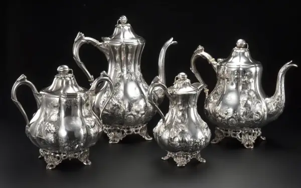 Un set di teiere e lattiera in argento antico, finemente cesellate con motivi floreali, un vero tesoro di grande valore.